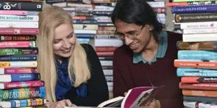 Two women reading amongst a pile of books