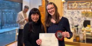 Photo of Jess on the right with her mentor Atsuko on the left showing her certificate to the camera