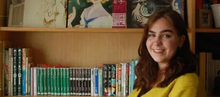 Photo of Francesca standing in front of a bookcase with her collection