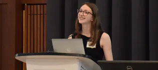 Photo of a student standing at a podium delivering a talk