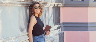 Ines standing by a wall holding a notebook