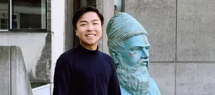 Photo of a student with a statue to his left