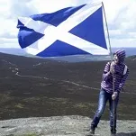 Girl planting a Scottish flag on a mountain