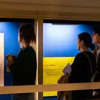 Photo of a group of visitors to Talbot Rice Gallery looking at one of the panels from the exhibition the nature of difference