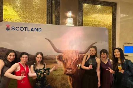 Group of students posing in front of banner with highland cow and the text Scotland