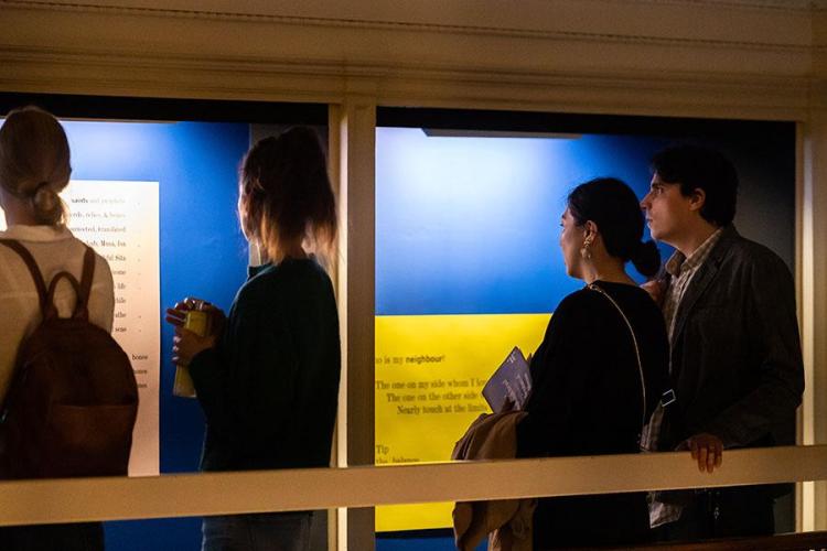 Photo of a group of visitors to Talbot Rice Gallery looking at one of the panels from the exhibition the nature of difference