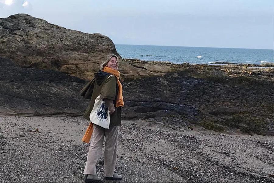 Photo of Elisabeth standing on the seashore looking directly at the camera