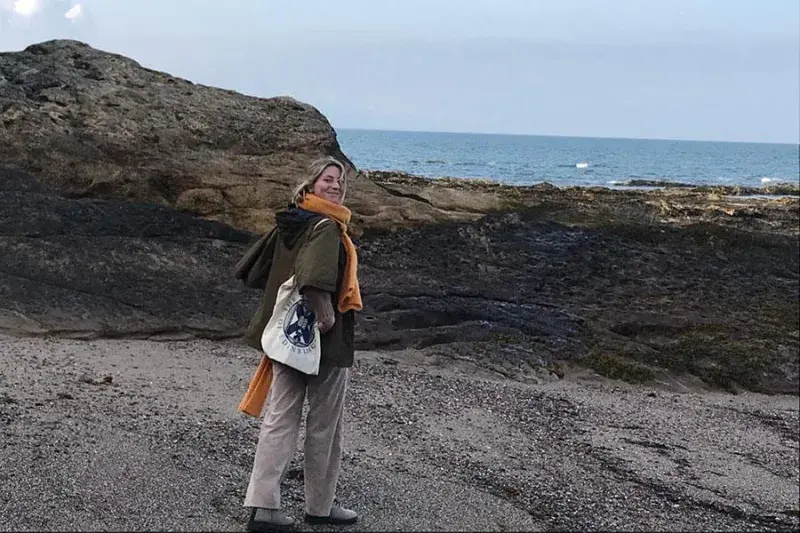 Photo of Elisabeth standing on the seashore looking directly at the camera