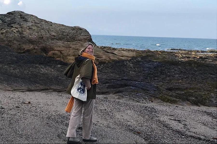 Photo of Elisabeth standing on the seashore looking directly at the camera