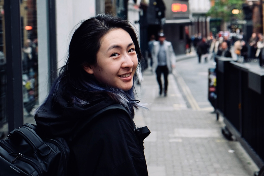 Ai Jiang looks looking over her shoulder, smiling at the camera