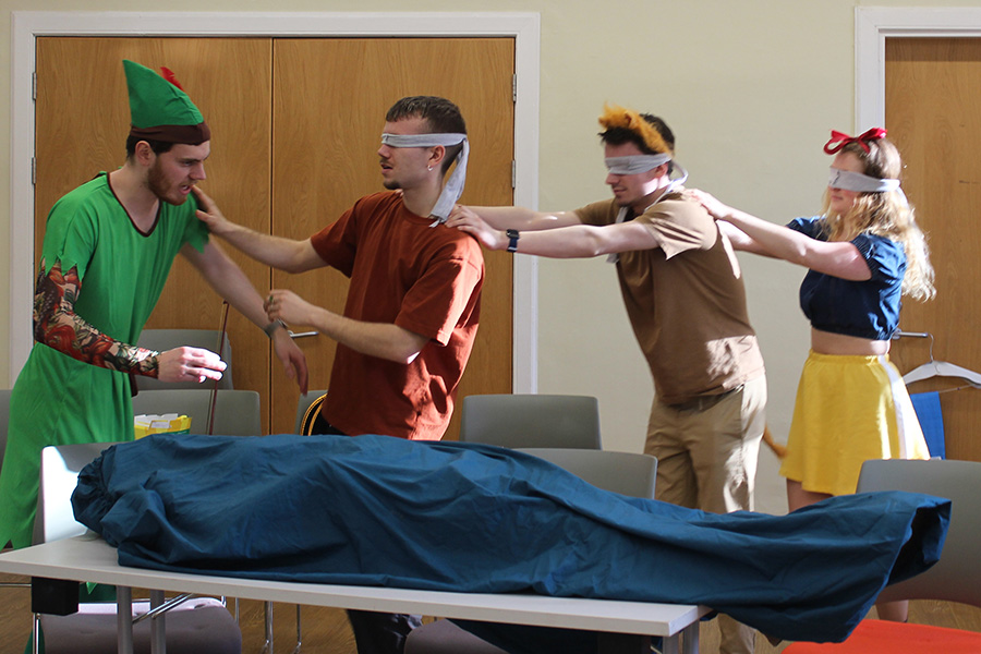 A photo of three people wearing blindfolds in a rehearsal for a play