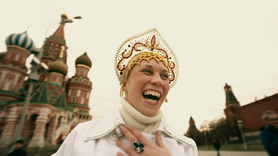 a woman in traditional Russian religious dress stands on Red Square laughing 