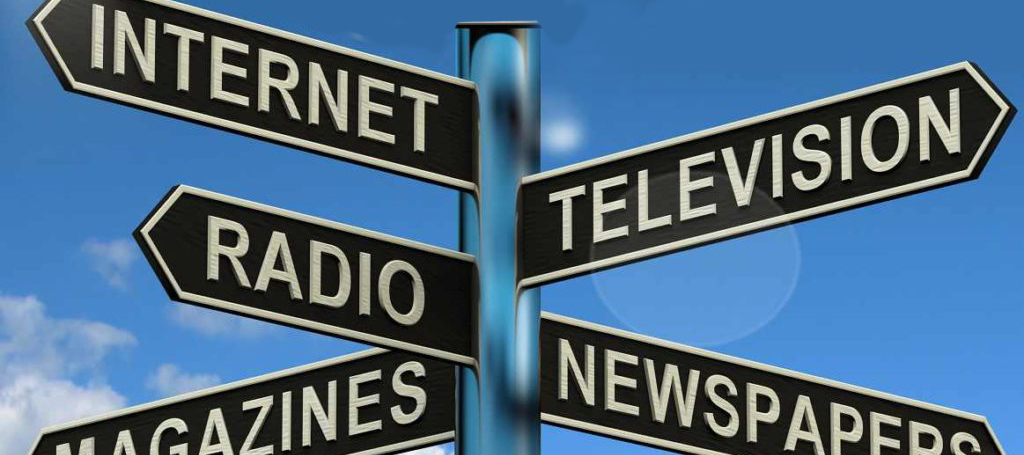 A road sign with the words internet, radio, magazines, newspaper and television pointing in different directions