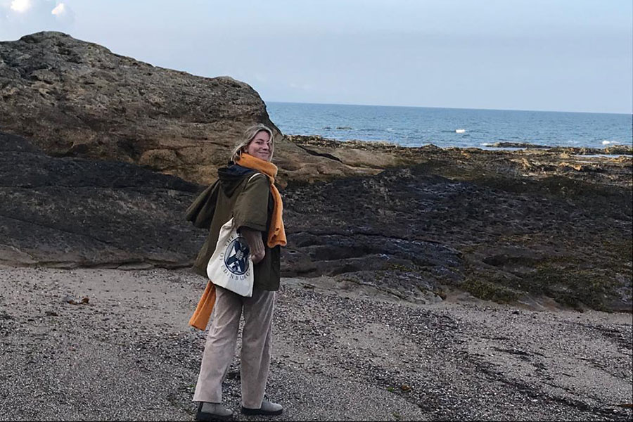 Photo of Elisabeth standing on the seashore looking directly at the camera