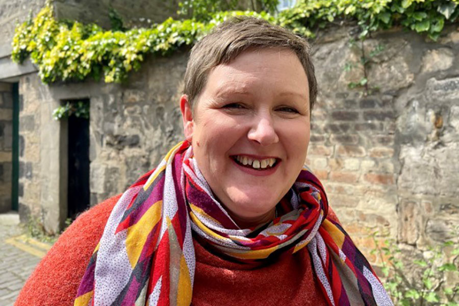 Photo of Lynn standing outside in a cobbled lane looking at the camera