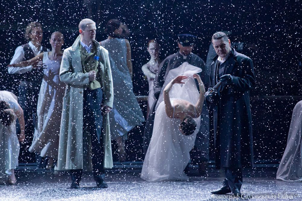 a dramatic snowy theatre scene with actors including a woman in a dress onstage