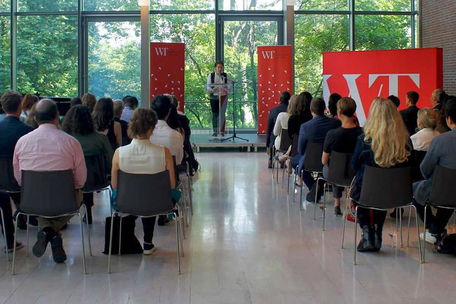 Photo of a poet reading to a room full of people