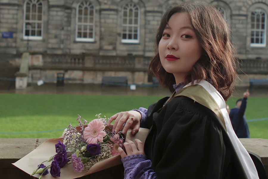 Photo of Yixiang Shirley Lin on graduation day standing outside Old College